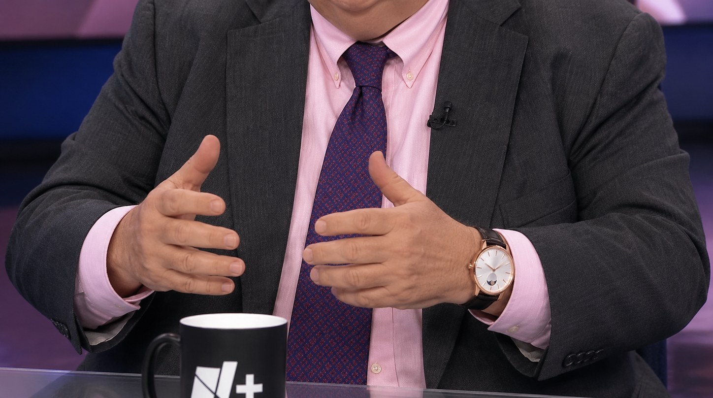 Hombre de traje con un reloj mecánico en acabado oro rosa en la muñeca durante una entrevista