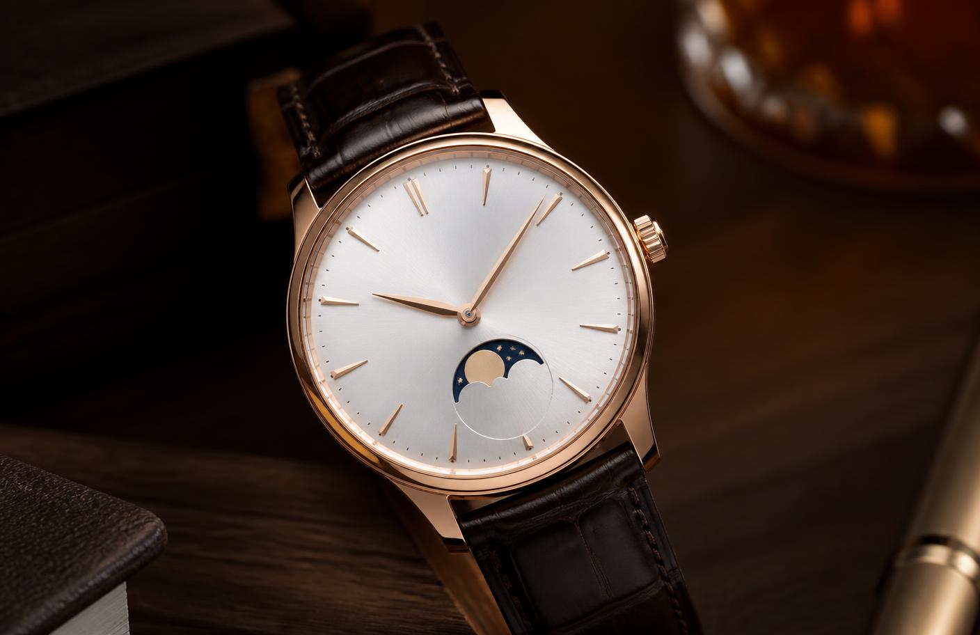 Reloj mecánico en acabado oro rosa con carátula blanco plata y correa de piel café sobre una mesa de nogal